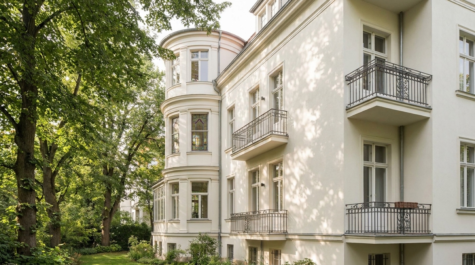 Historische Berliner Altbau-Villa mit weißer Fassade, von der Seite, eingebettet in alte Bäume