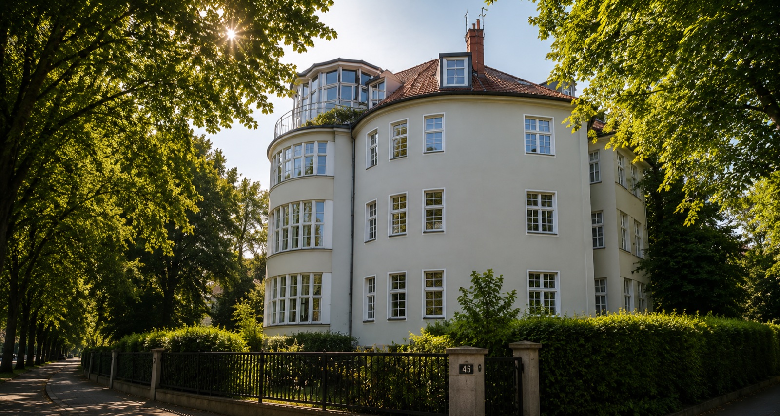 Campus Living Berlin Gebäude — historische weiße Fassade mit Erkern, eingebettet in alten Bäumen in Berlin-Zehlendorf